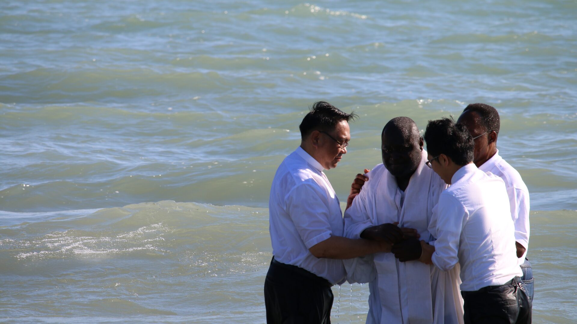 Four Individuals Wearing White Near the Beach