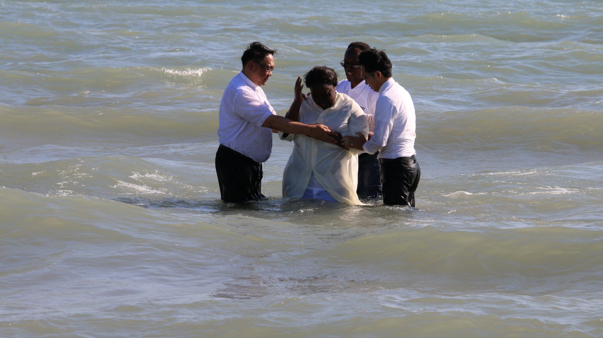 Four Individuals Wearing White Near the Beach