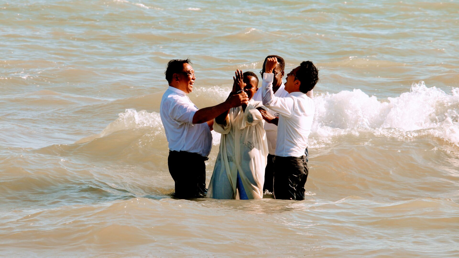 Four Individuals Wearing White Near the Beach