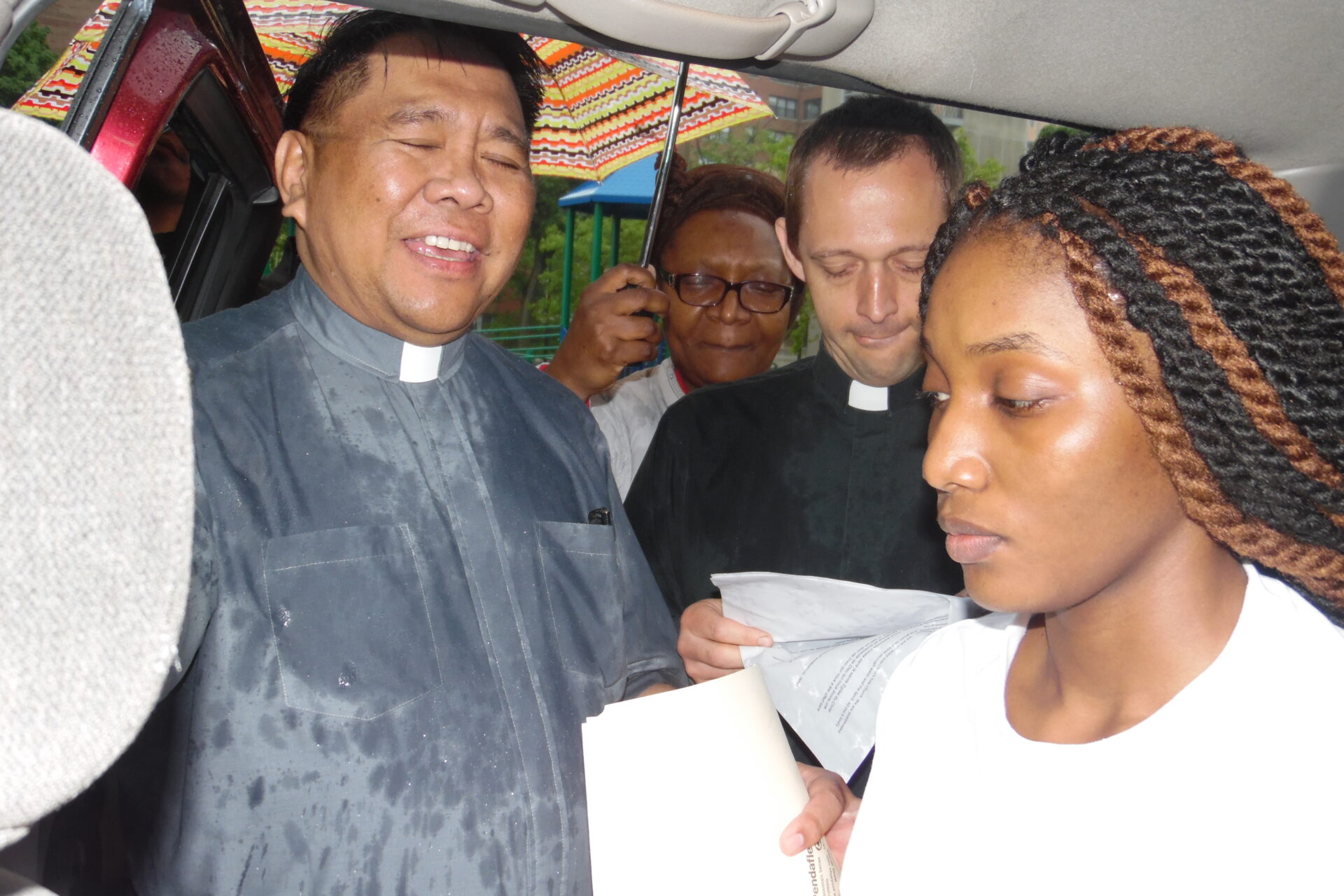 A Woman Inside a Car Surrounded by People From the Church