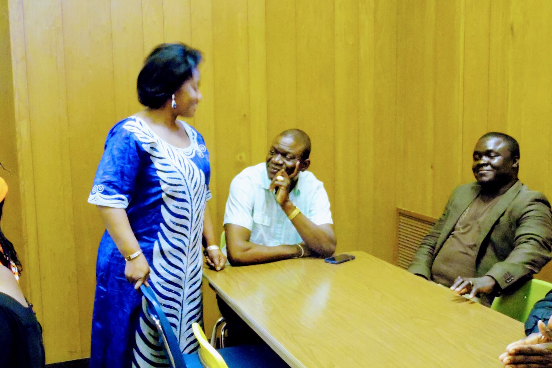 A Woman Standing and Two Men Sitting